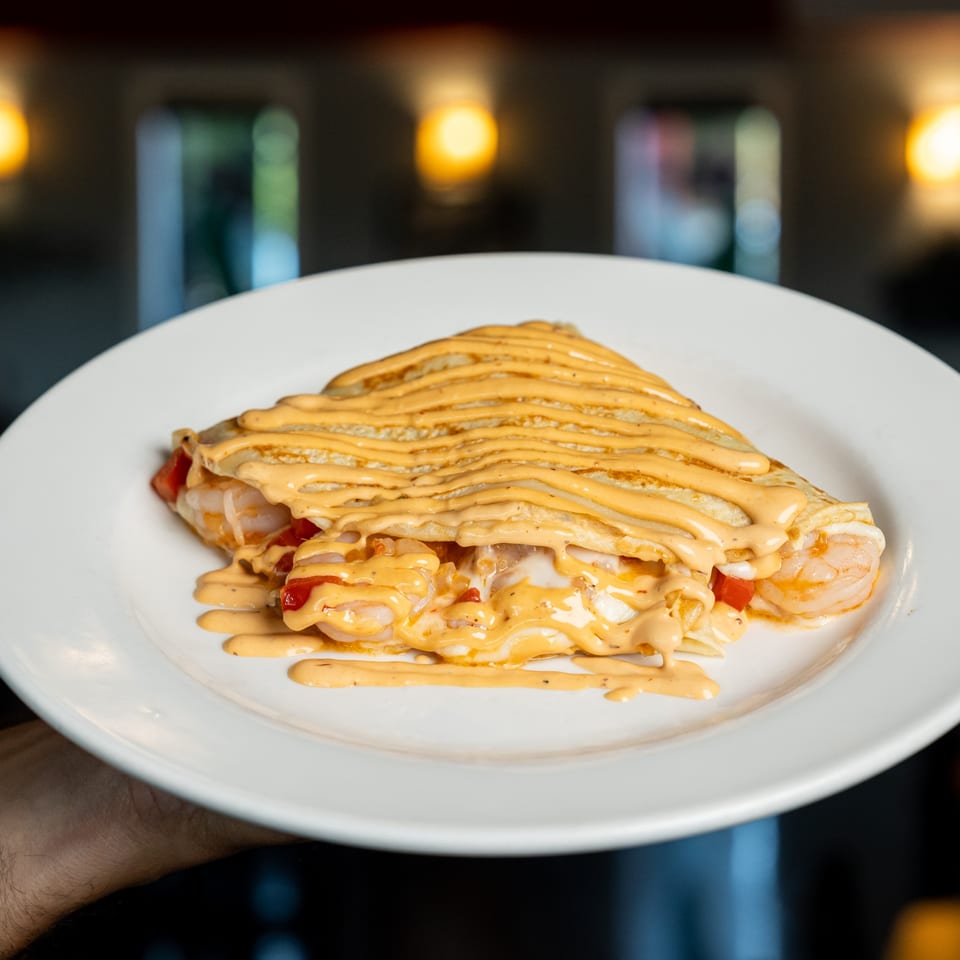Savory crepe from Kely's Crepes & Burgers, filled with shrimp and red peppers, drizzled with sauce.